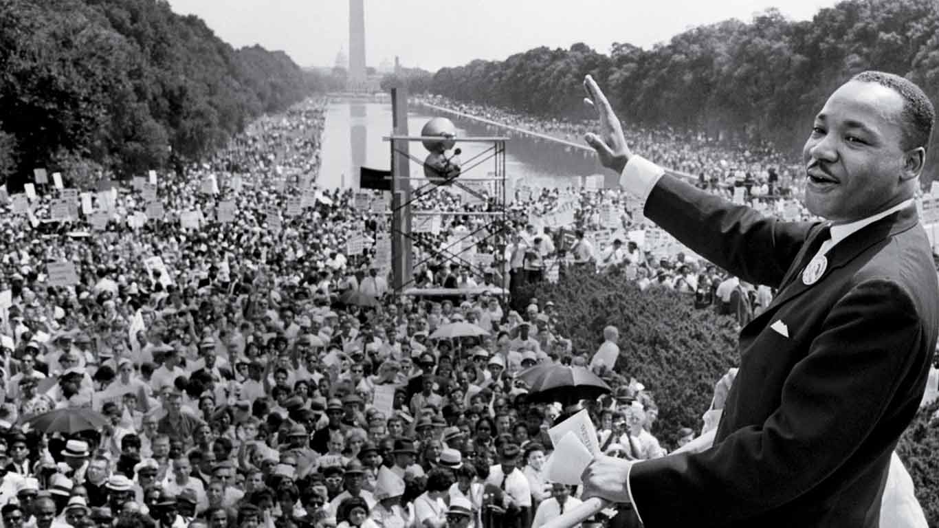 Marting Luther King waving his hand to a large crowd